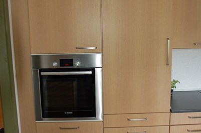 Integreret køleskab til højre, med ovn hævet op til rigtige arbejdshøjde til venstre